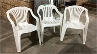 Three white plastic stackable chairs