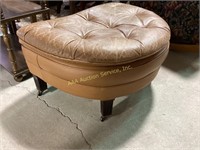 Leather ottoman with wooden legs and wheels.