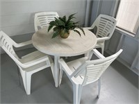 Table and 4 chairs with plant.