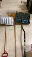 A leaf rake and two snow shovels. One of the snow