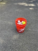 Bucket of baseballs and a softball