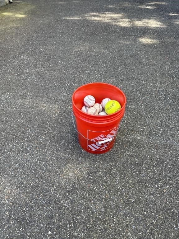 Bucket of baseballs and a softball