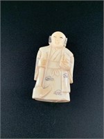 Antique netsuke of a man holding a hoe and drink.