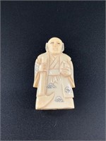 Antique netsuke of a man holding a hoe and drink.