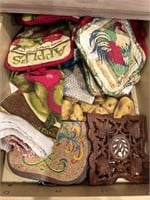 Lot of kitchen towels, trivets, and oven mitts.
