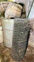 Partial roll of fence wire, plastic barrel