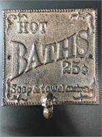 Cast iron wall hook that says "Hot BATHS 25¢". It