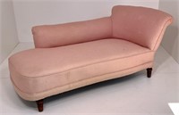 Pink upholstered chaise, long arm on back, turned