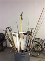 Large trash can full of gardening tools brooms