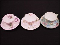Three decorative cups and saucers: two are
