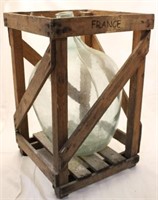 Large glass jug in wood crate