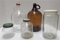 Group of glass jars and one gallon jugs.