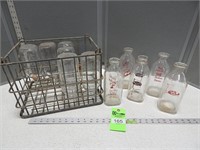Metal milk crate with milk bottles; some have dair