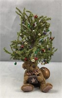 Small bear under a miniature Christmas tree