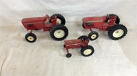 Three red toy tractors