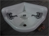 Lavabo en coin en fonte à deux robinets
