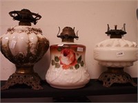Three vintage oil lamps, all with milk glass fonts