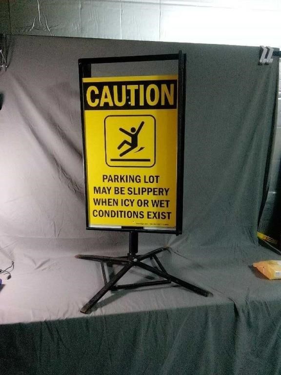 Large caution sign on heavy metal swivel base.