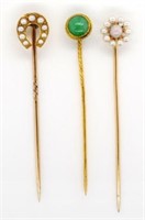 A group of three gold and gemstone stick pins