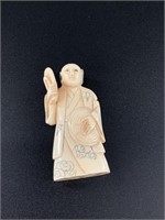 Antique netsuke of a man holding up a shoe. Approx