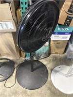 Lasko black colored standing fan, plugged in and