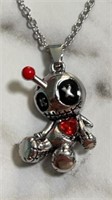 Voodoo doll with shiny red heart necklace.