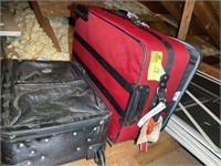 Pair of rolling suitcases, one red fabric, one bla