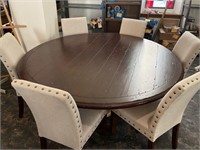 6 foot round wood table with 6 white chairs.