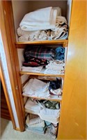 Hallway closet with blankets, sheets, table