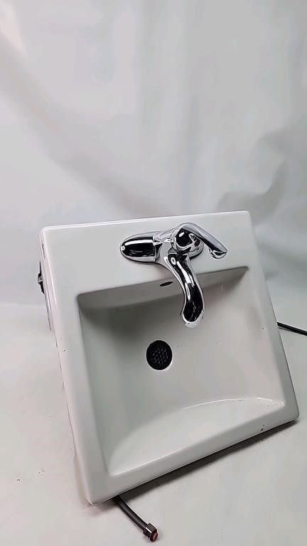 Ceramic sink with tape and plumbing attached