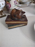 Hand carved cat asleep on a stack of books.