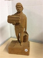 Wood carving of man carrying wood and bucket