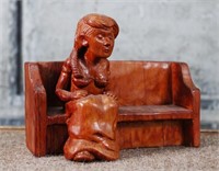 A Carved Wood Sculpture of a woman on park bench,