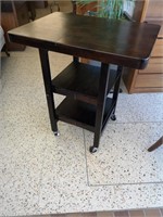 Dark wooden kitchen foldable island on casters.