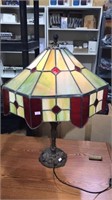 Metal base lamp with stain glass shade that has