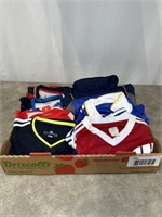 Assortment of soccer jerseys and shirts, most are