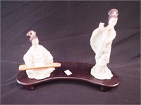 Two geisha figurines playing musical instruments: