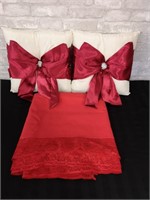 Lovely red tablecloth and decorative pillows.