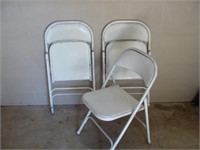 Three White Folding Chairs