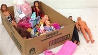 Group of barbies and ken dolls with clothes and