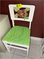 White chair with green seat, decorative flower on