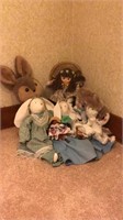 Stuffed bunnies, dolls, wicker chair.