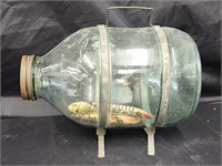 Unmarked glass minnow trap with metal legs and
