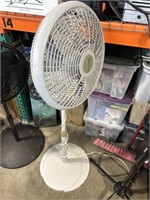 Lasko gray colored standing fan, plugged in and