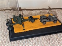 Military model jeep and artillery under glass