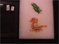 Two Oriental-style pins of a geisha and dragon