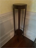 Plant stand with ornate design on top and shelf