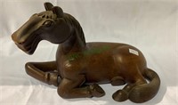 Handcarved wooden horse laying down, with a