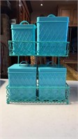 Metal teal canisters on a sitting or hanging rack
