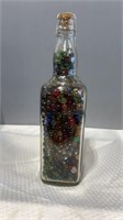 Large bottle full of clear marbles.